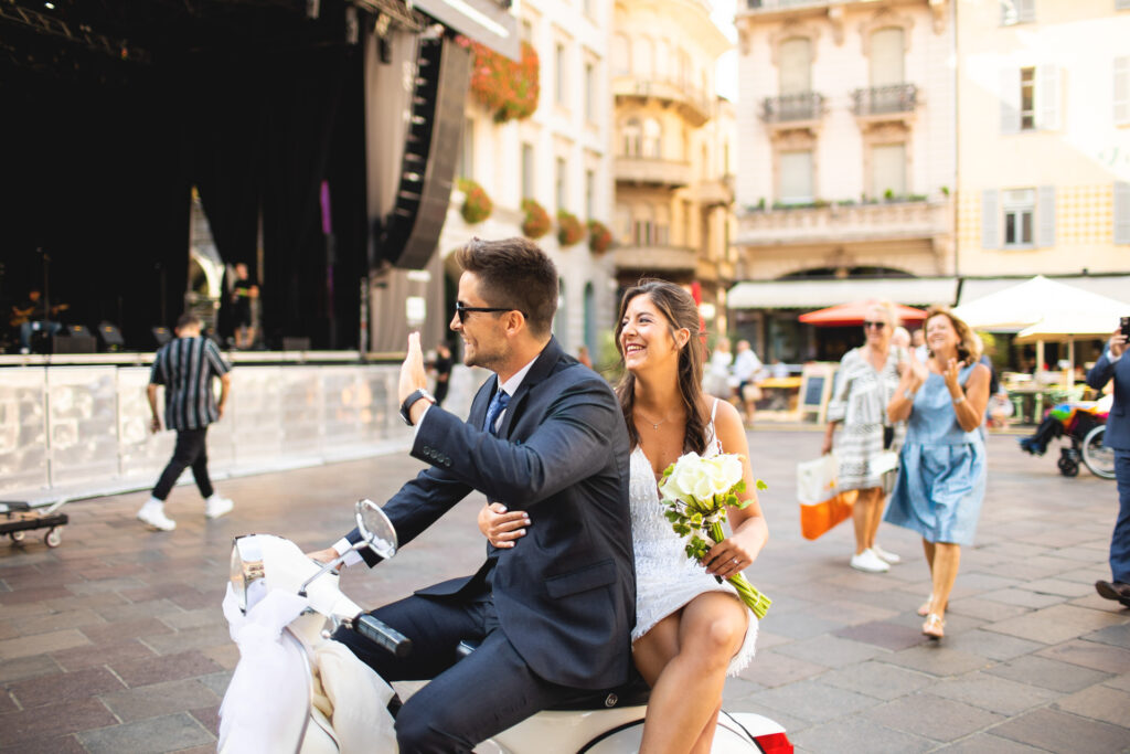 Reportage fotografico arrivo sposi in vespa in piazza a Lugano