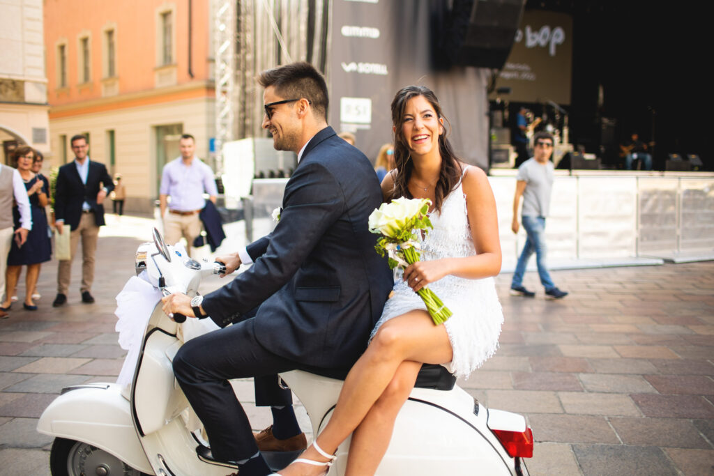 Reportage fotografico arrivo sposi in vespa in piazza a Lugano