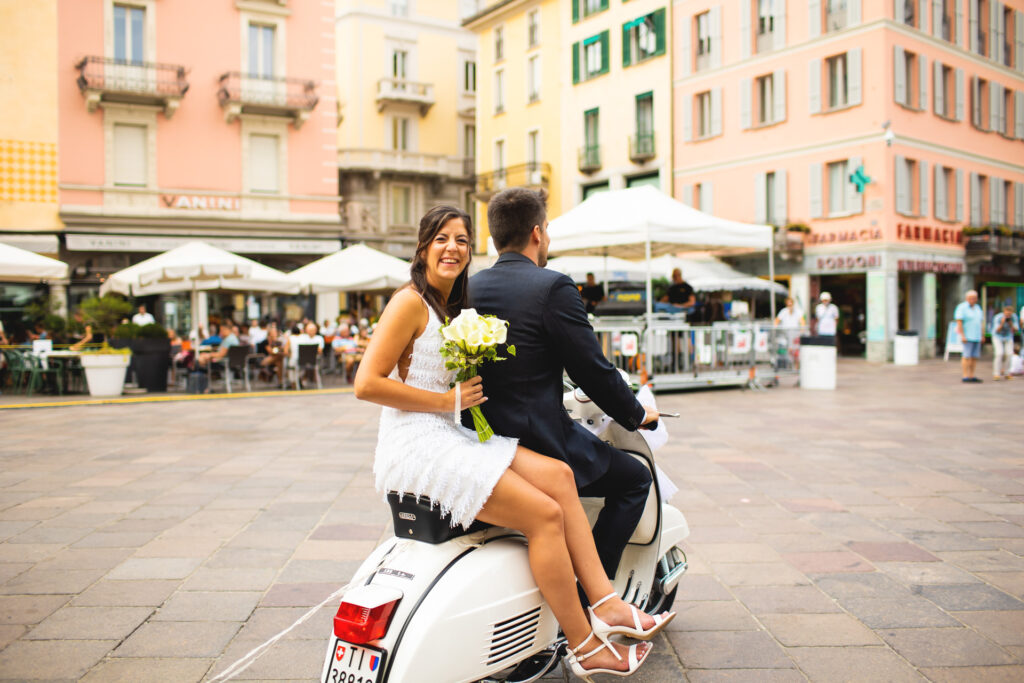 Reportage fotografico arrivo sposi in vespa in piazza a Lugano